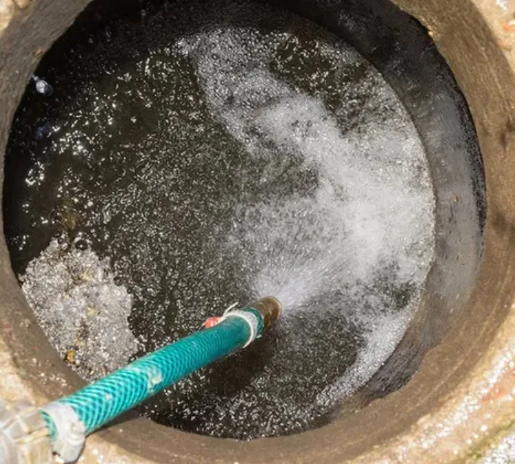 Septic tank cleaning with high-pressure water hose during professional septic system maintenance