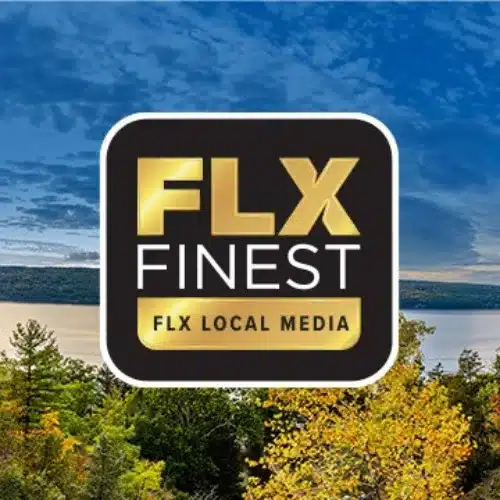 Logo for "FLX Finest" by FLX Local Media, featuring bold gold and white text on a black background with rounded corners. The logo is set against a scenic backdrop of Finger Lakes region trees in autumn and a lake under a partly cloudy sky.