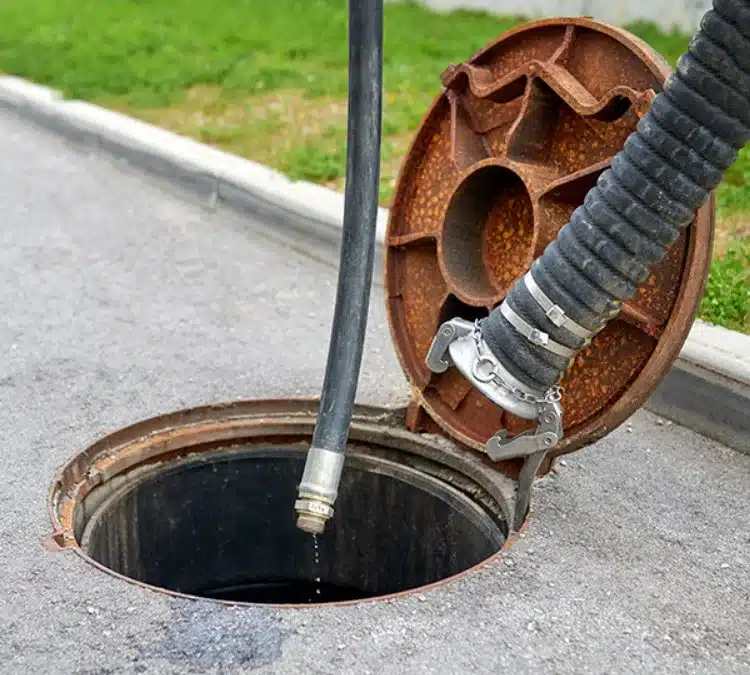 Septic tank access cover with a vacuum hose for residential pumping services, highlighting maintenance and repair work by PumperJack Septic.