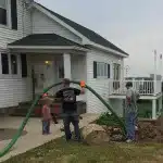 Technicians from PumperJack Septic performing residential septic system maintenance at a rural home in the Finger Lakes, with equipment and vacuum hose in use