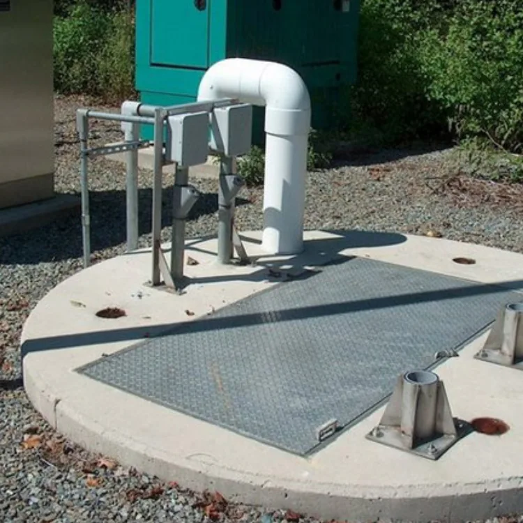 Industrial Lift Station Cleaning Lift station cleaning equipment with a metal access cover and piping, set in an industrial environment for wastewater management.