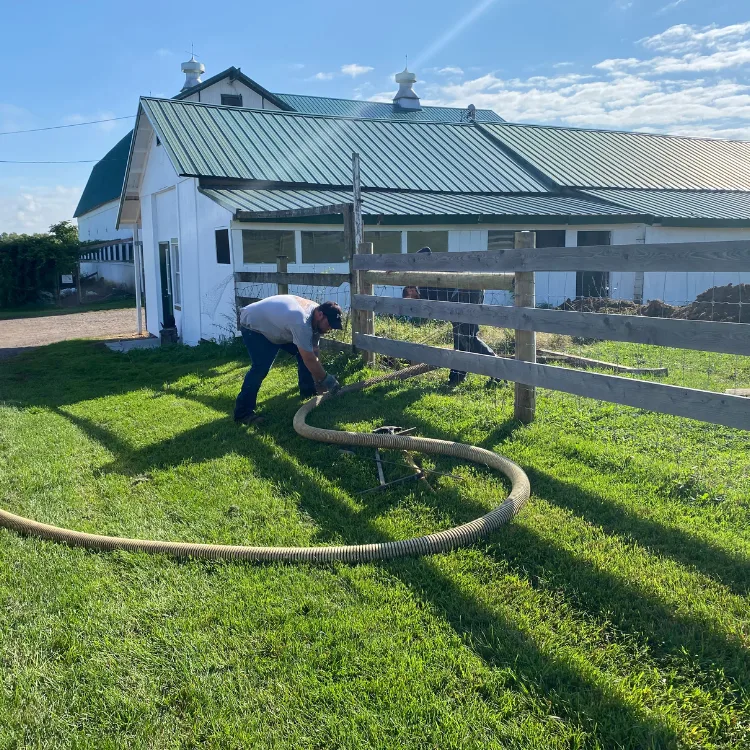 Residential Drain Cleaning Technician cleaning a residential drain pipe using mechanical equipment outside a farm in the Finger Lakes