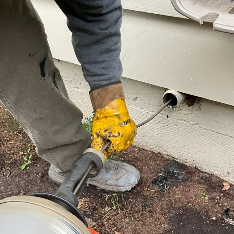 Residential Drain Snaking Close-up of a PumperJack Septic technician snaking a clogged residential drain through an exterior cleanout access point