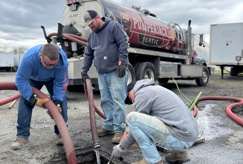 PumperJack Septic crew servicing an open manhole with vacuum hoses and a tanker truck during lift station cleaning and sewer clean-out work
